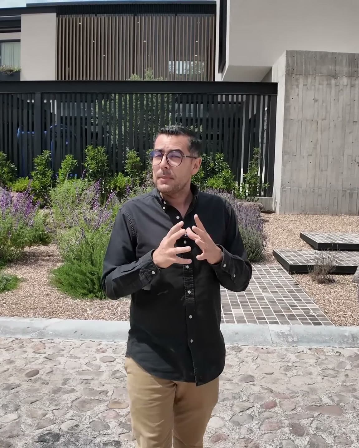 El Arqui Diego, arquitecto y consultor inmobiliario, explicando el proyecto frente a una casa contemporánea durante un recorrido de obra